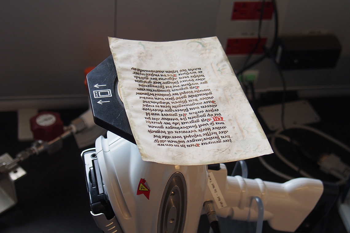 Old manuscript page on top of a XRF hand-held spectrometer.