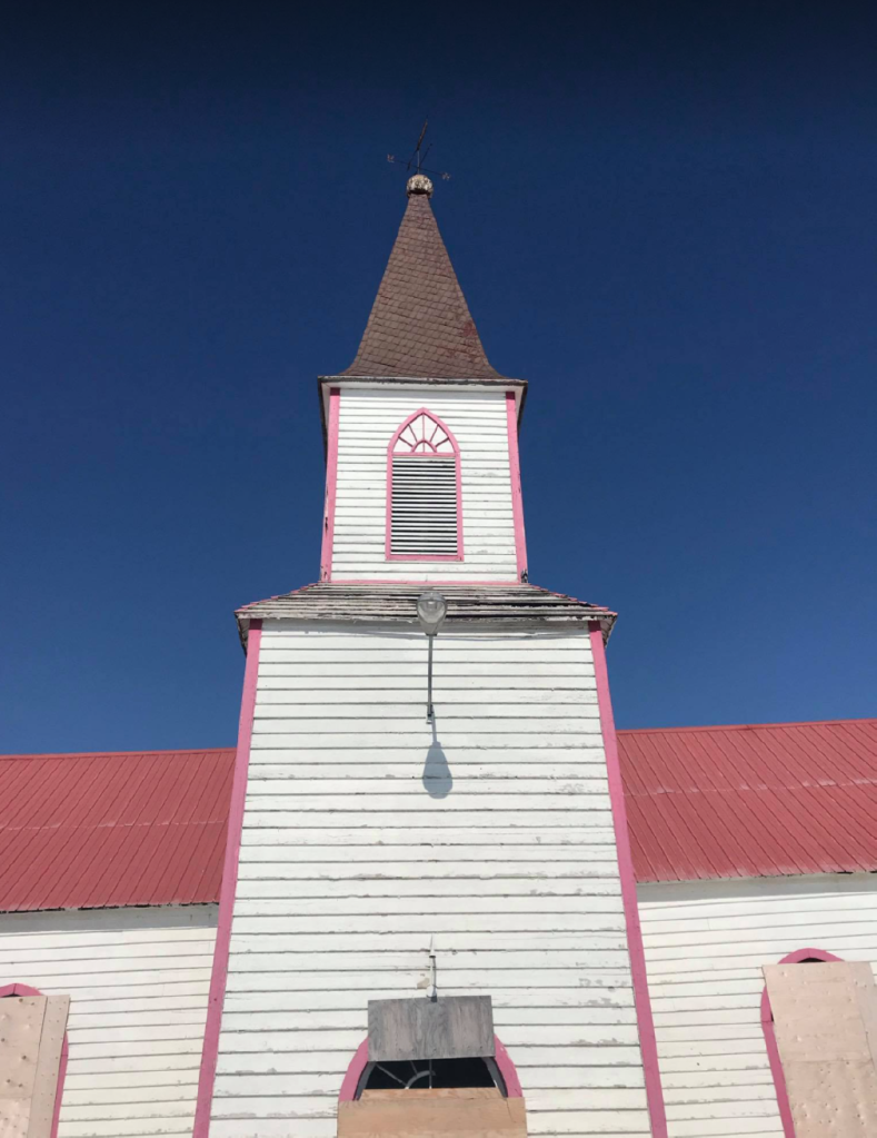 The church’s tin roof spire has rusted over time, while many of the building’s red accents have faded to pink in the sun. Photo: Miyopin Cheechoo